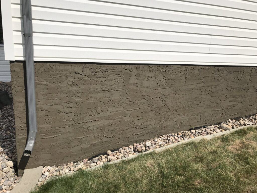 Parging on house exterior in Edmonton Parging application on the lower exterior wall of a house in Edmonton.