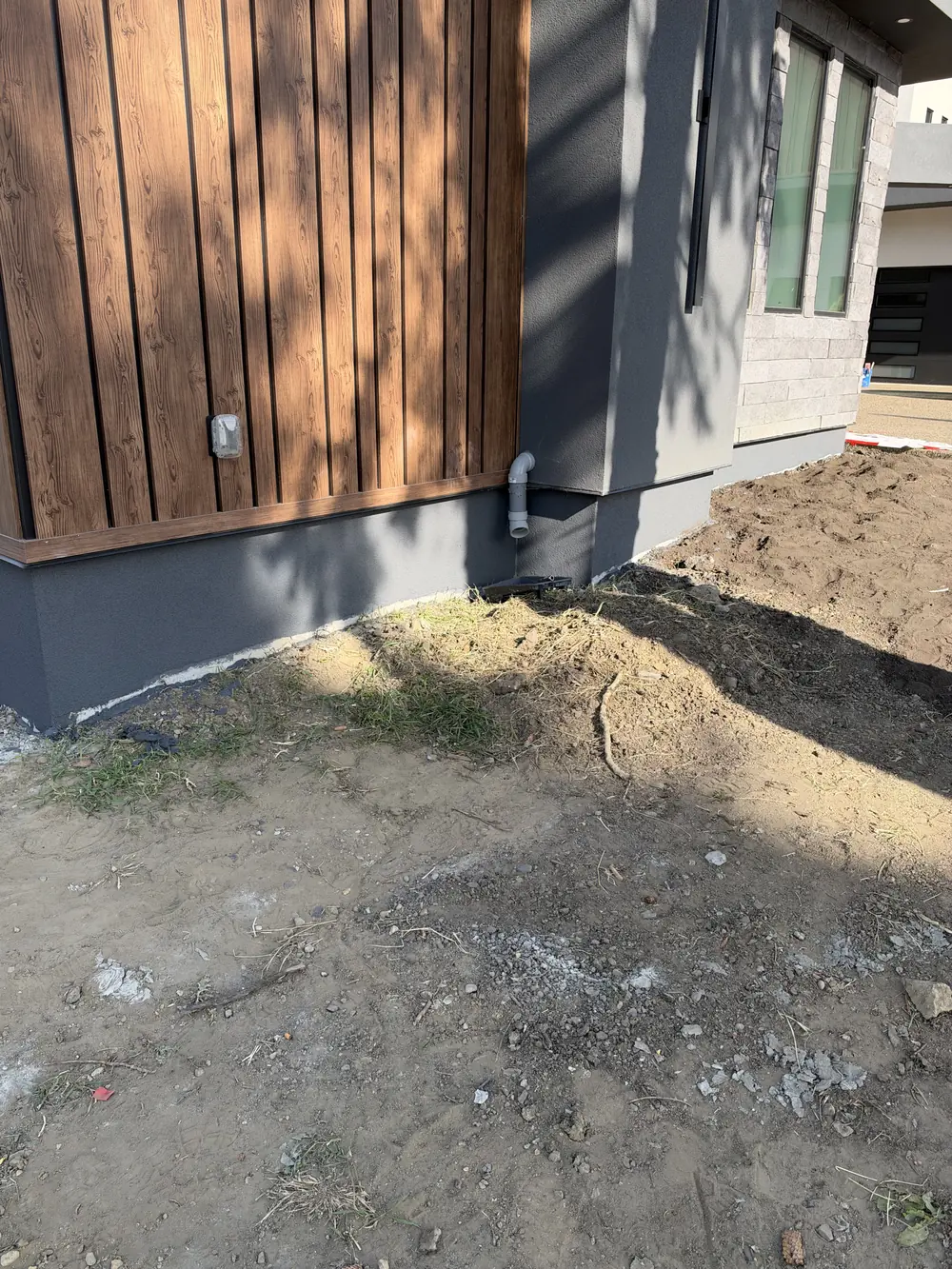 Grey acrylic foundation finish beneath white stucco and wood-look cladding