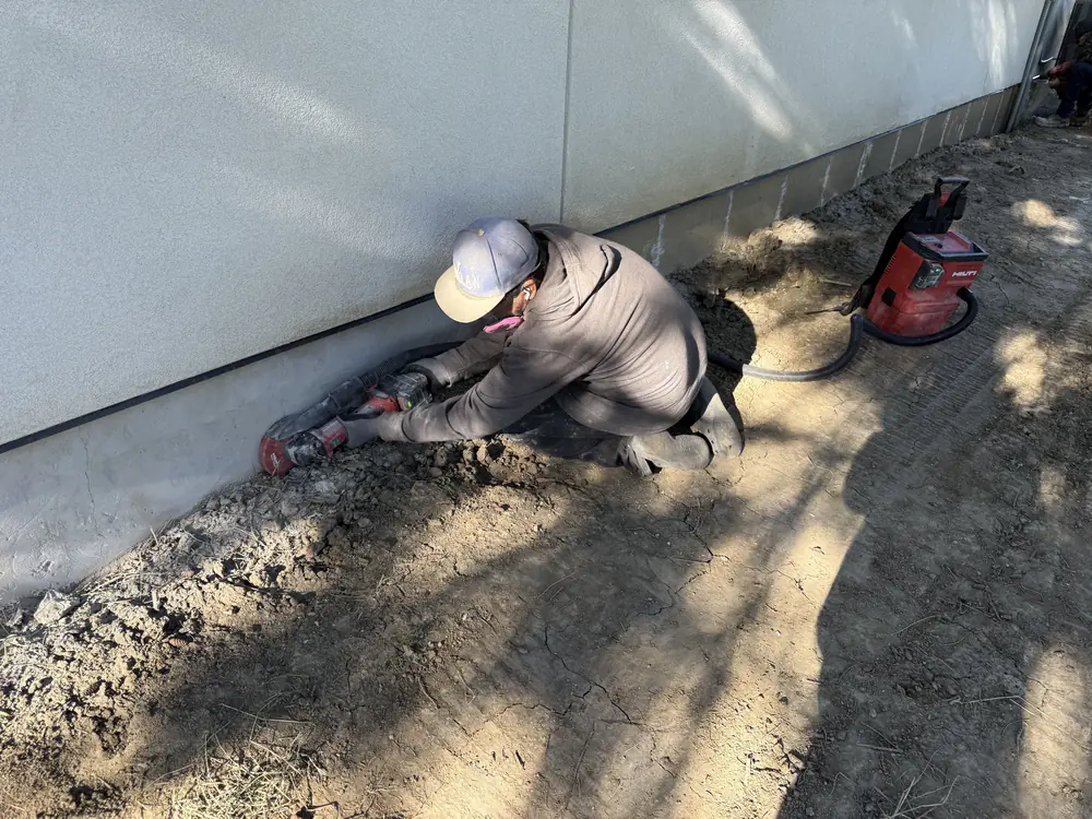 J and J Coatings crew member grinding the concrete foundation surface